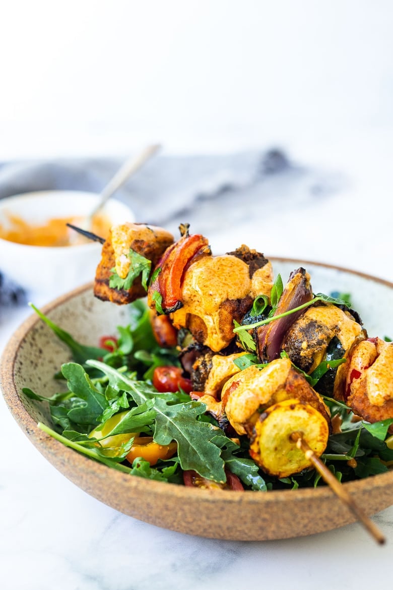 Grilled Veggie Kabobs with Harissa Yogurt -made with your choice of protein (tempeh, tofu,or chicken)! A delcious summer meal that packs a big punch of flavor! Perfect for summer bbqs and gatherings! Served over greens in a bowl.