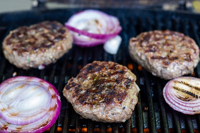 bison burger patties on the grill with grilled onions