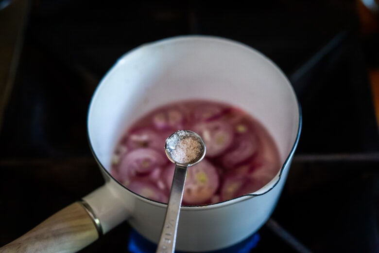 Adding salt to the pickled shallots.