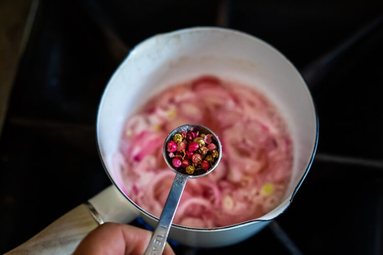 Adding peppercorns to the pickled shallots.