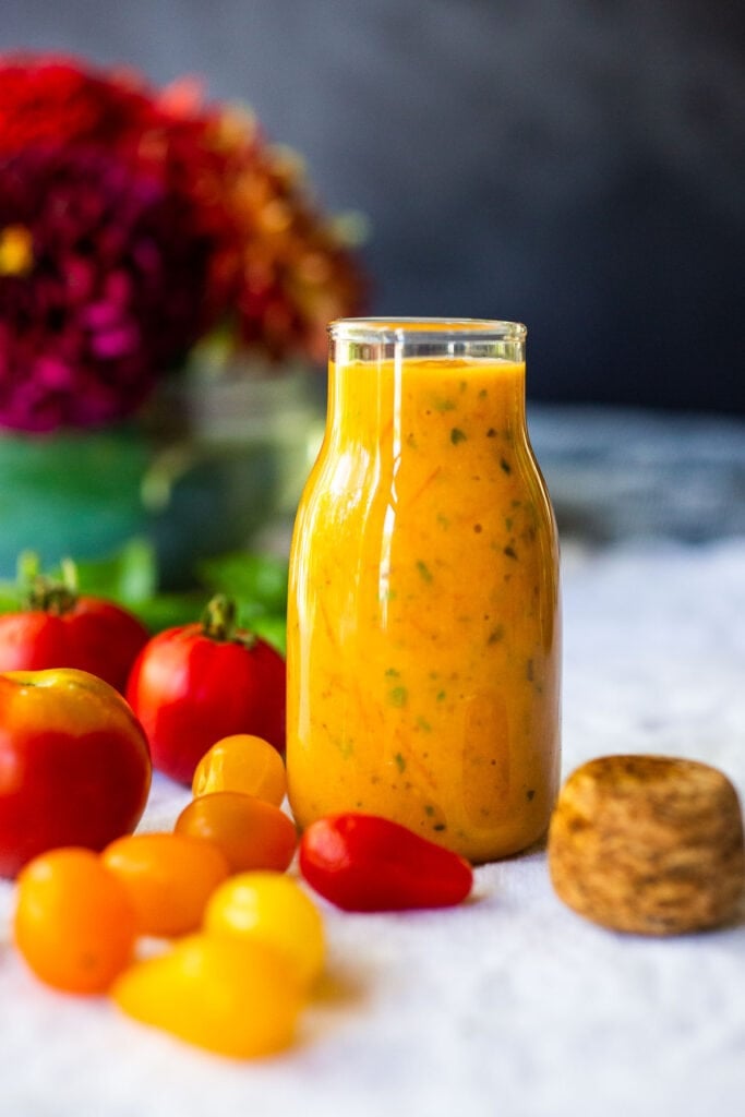 jar of tomato vinaigrette next to whole tomatoes. 