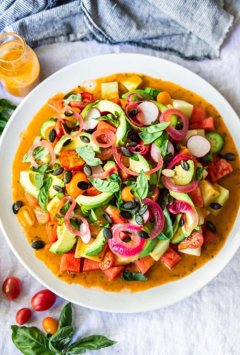 A refreshing Tomato Watermelon Salad with cucumber, radishes, avocado, basil, pumpkin seeds and pickled shallots tossed in the most flavorful Tomato Vinaigrette. Vegan and Gluten-free.#tomatosalad #melonsalad