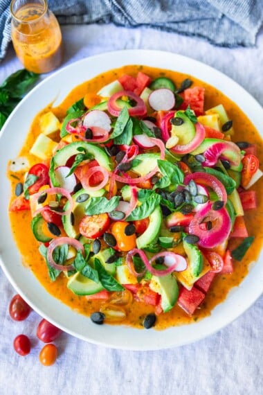 Cooling, refreshing Tomato Watermelon Salad with melon, avocado, pickled shallots, radishes, pumpkin seeds, and basil,  tossed in a flavorful Tomato Vinaigrette. Vegan and Gluten-free.