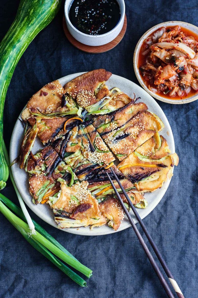 These Korean-inspired Zucchini Scallion Pancakes are a simple tasty treat!  No-fuss preparation and ready to serve in minutes.  Packed with zucchini and scallions, held together with rice flour and eggs, heavy on the veggies.  Seasoned with gochujang pepper chili paste and a touch of rice wine, they are filled with savory flavor.