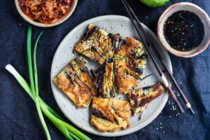 These Korean-inspired Zucchini Scallion Pancakes are a simple tasty treat!  No-fuss preparation and ready to serve in minutes.  Packed with zucchini and scallions, held together with rice flour and eggs, heavy on the veggies.  Seasoned with gochujang pepper chili paste and a touch of rice wine, they are filled with savory flavor.