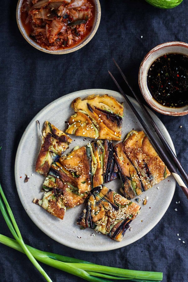 These Korean-inspired Zucchini Scallion Pancakes are a simple tasty treat!  No-fuss preparation and ready to serve in minutes.  Packed with zucchini and scallions, held together with rice flour and eggs, heavy on the veggies.  Seasoned with gochujang pepper chili paste and a touch of rice wine, they are filled with savory flavor.