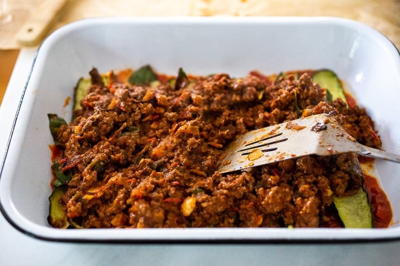 spreading the meat sauce over the zucchini 