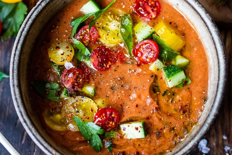 Smooth Gazpacho in a bowl topped with tomatoes and cucumber