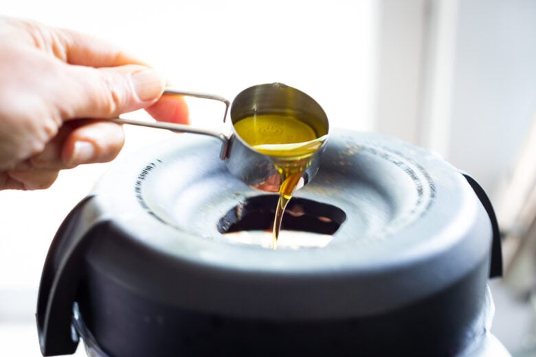 adding the olive oil to the gazpacho.