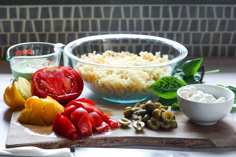 pasta in a bowl with chopped veggies ready to mix in