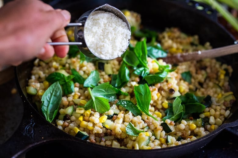 adding pecorino and basil leaves to the pasta