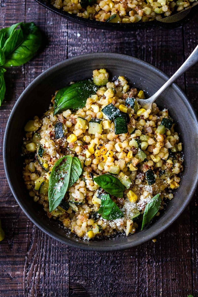 bowl of fregola sarda with corn, zucchini, pecorino, and basil.