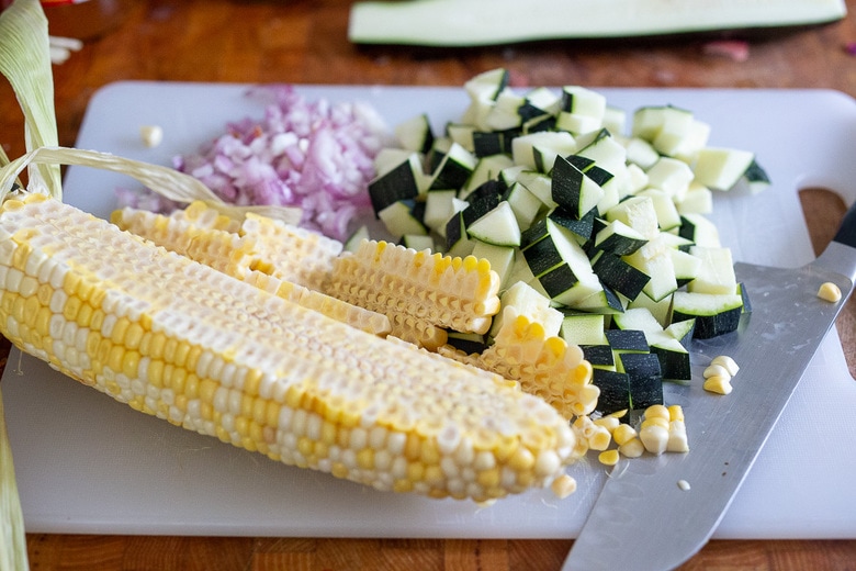 Chopped corn, shallot, garlic and corn on a cutting board.