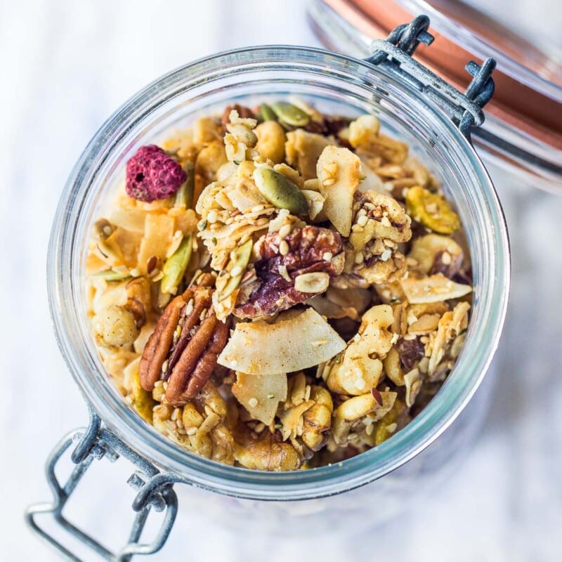 Full of irresistible nutty clusters, this healthy, vegan, gluten-free granola recipe is easy and delicious! Made with oats, nuts, seeds, and dried fruit, warming spices, coconut oil, sweetened with maple syrup. Only 10 minutes of hands-on time before baking in the oven! Video.