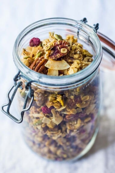 Full of irresistible nutty clusters, this healthy vegan granola recipe is easy and delicious! Made with oats, nuts, seeds, and dried fruit, warming spices, coconut oil, sweetened with maple syrup. Only 10 minutes of hands-on time before baking in the oven! Video.