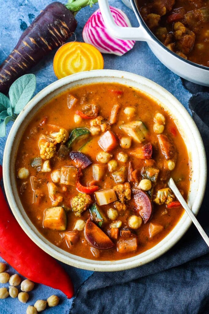 This Harvest Vegetable Soup recipe is so cozy and nourishing! Packed with seasonal veggies and chickpeas in a luscious roasted tomato base with fresh herbs. Vegan & delicious!