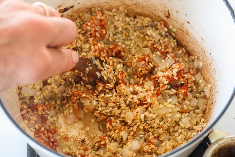 stirring tomato paste into the Mexican rice