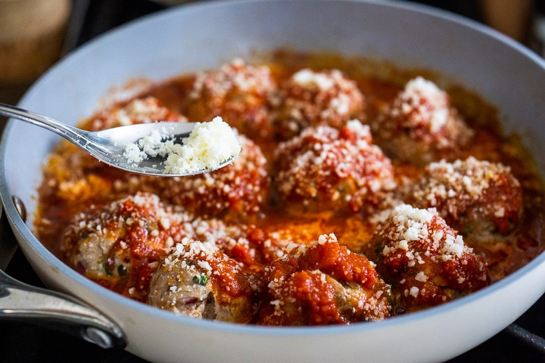 simmering the meatballs in marinara sauce and sprinkle with parmesan cheese 