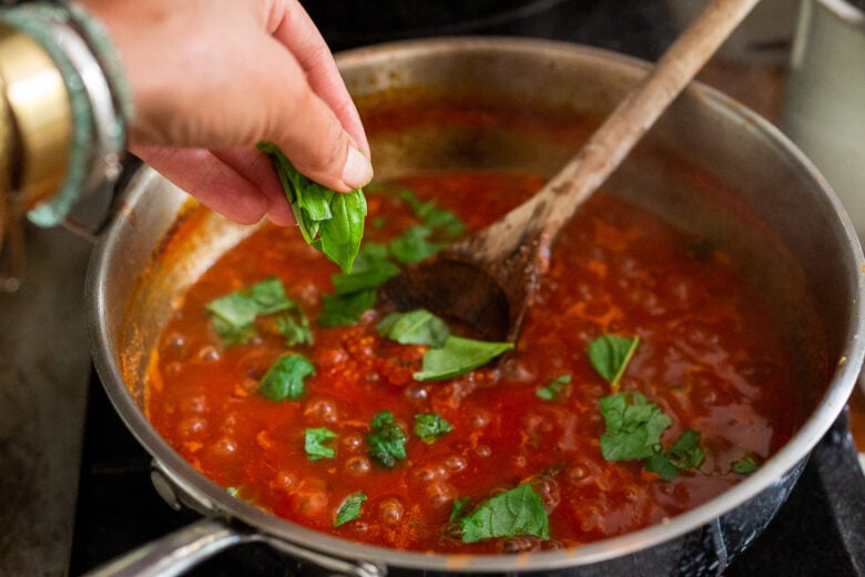 Fresh basil leaves in marinara sauce.