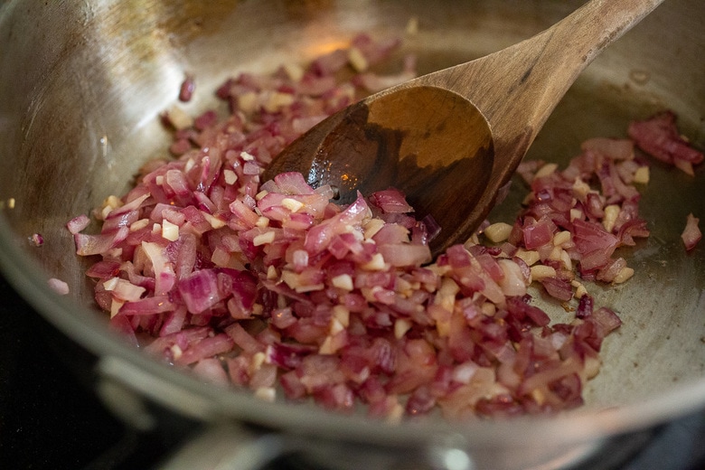 onions and garlic sauteing in a pan with olive oil 