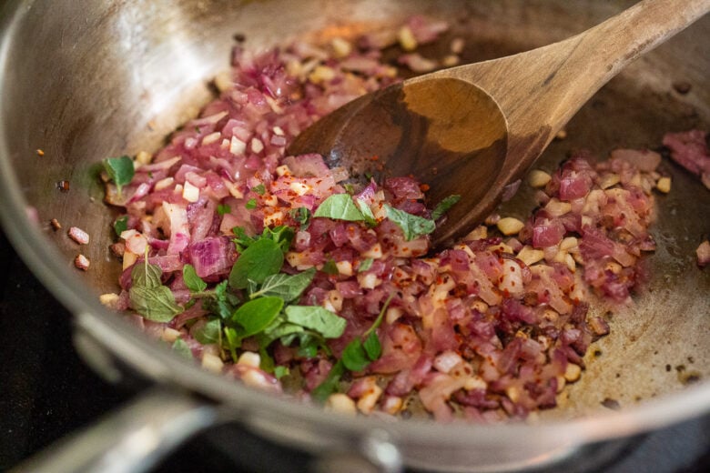 Sauteing onions, garlic, chili flakes and oregano in a pan.