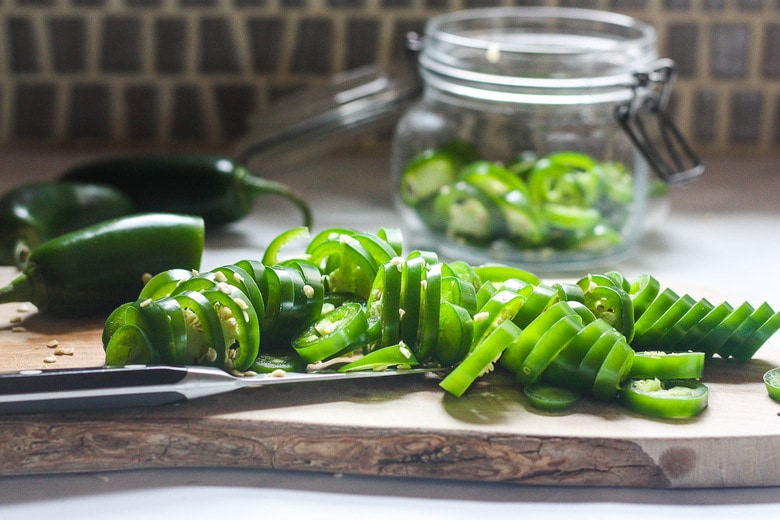 slicing jalapeños on a cutting board.