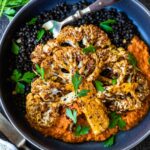 Roasted Cauliflower Steaks with flavorful Romesco Sauce over a bed of simply seasoned lentils. A quick and easy sheet pan dinner - vegan, plant-powered, and full of flavor!