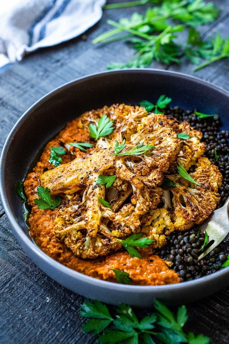 Roasted Cauliflower Steaks with Romesco Sauce over a bed of simply seasoned lentils. A simple, easy vegan dinner made on a sheet pan!