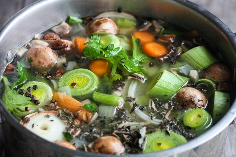 adding aromatics to the pot of simmering vegetable stock