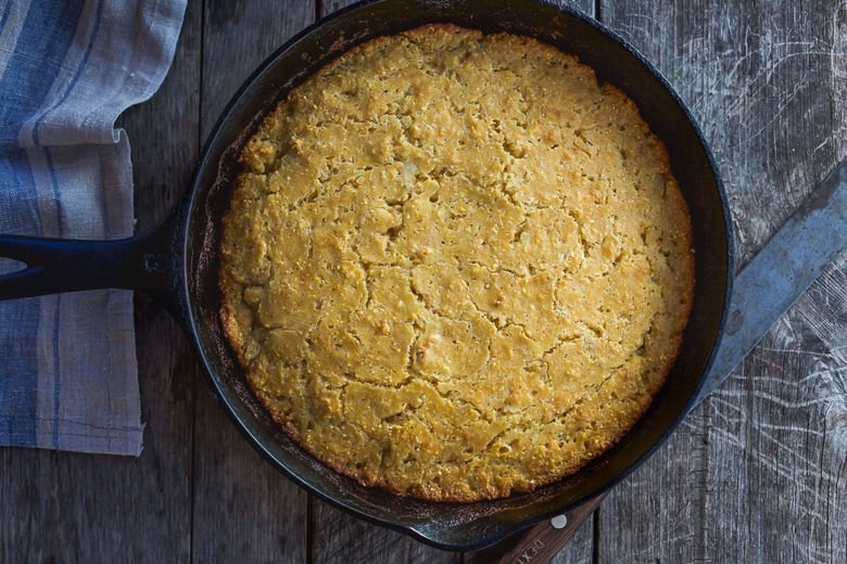 baked cornbread in round cast iron skillet.