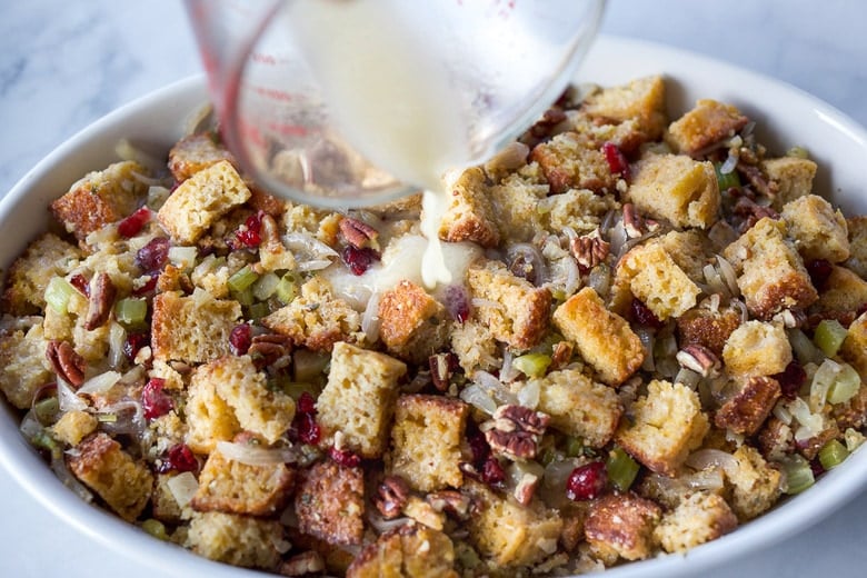 pouring broth over stuffing in baking dish