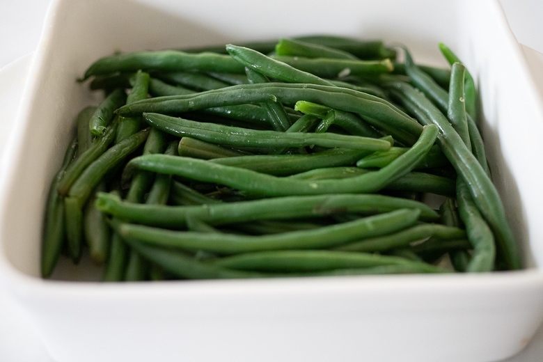 assemble the green bean casserole starting with green beans in a casserole dish 