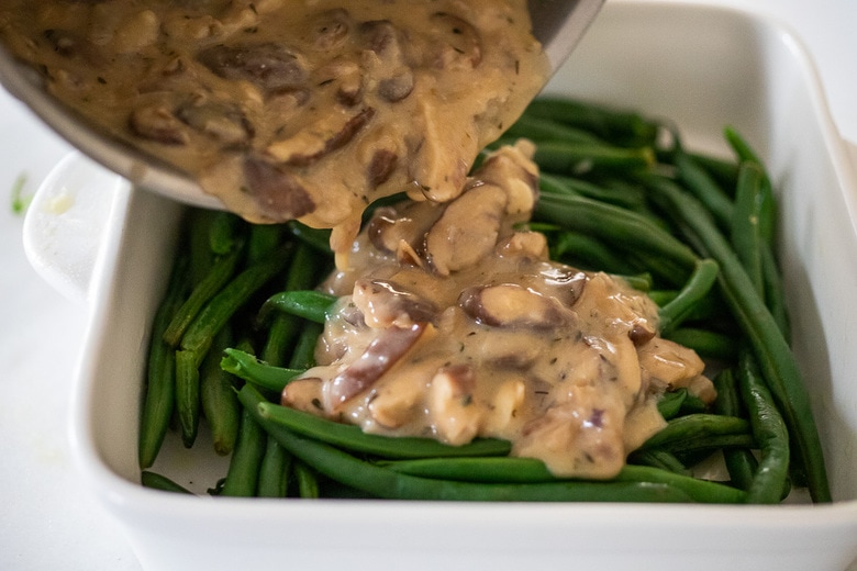 pouring mushroom sauce over the green beans
