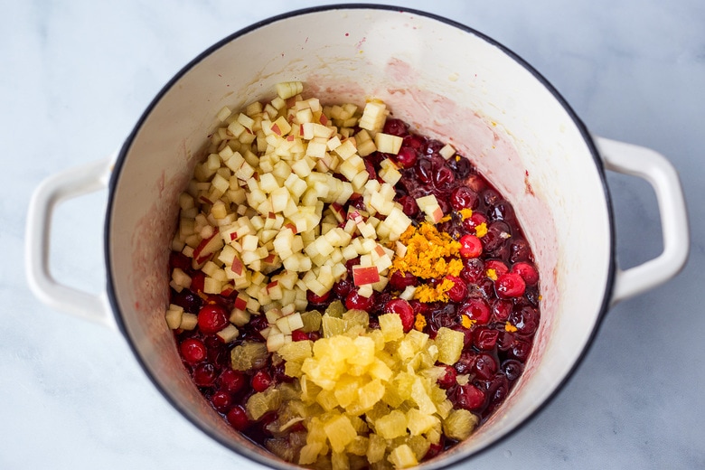 adding apple, zest and orange pieces to cranberries