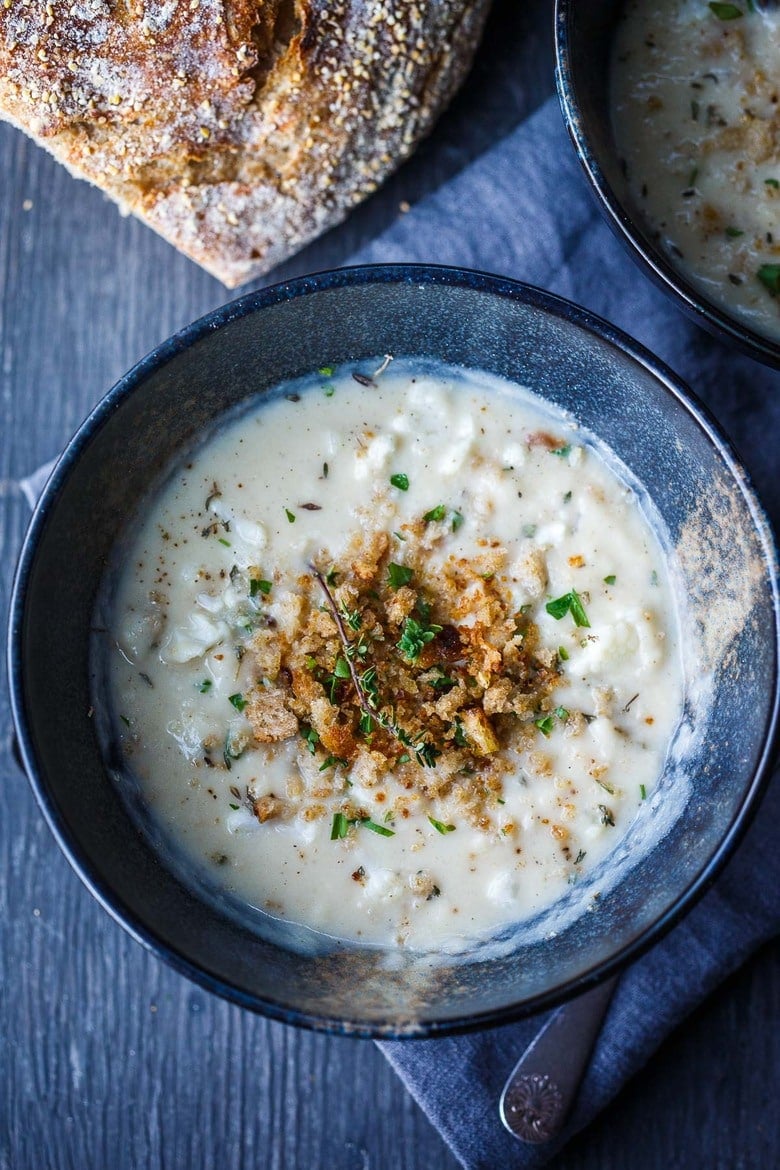 soup bowl with creamy Cauliflower Cheddar Soup, garnished with minced parsley and fresh thyme, and a bread crumb topping.