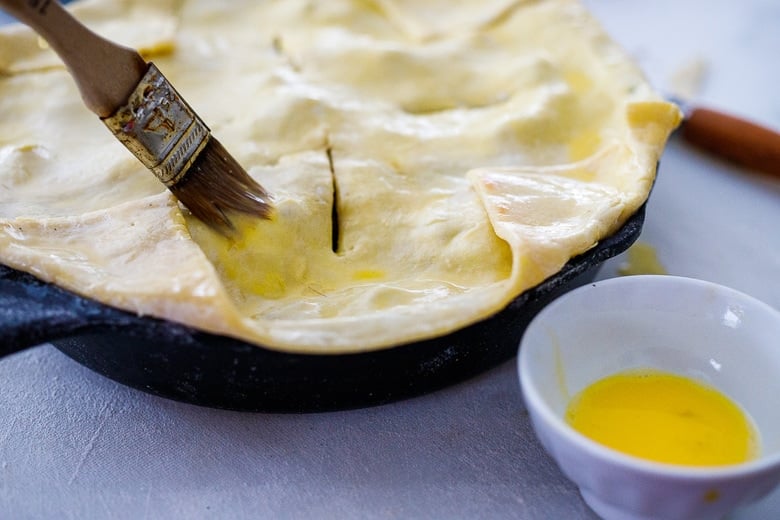 Fold up the corners of the puff pastry, slit the pot pie for venting and brush with olive oil or an egg wash