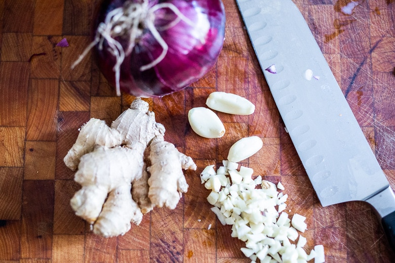 chopped onion and garlic and ginger on a cutting board