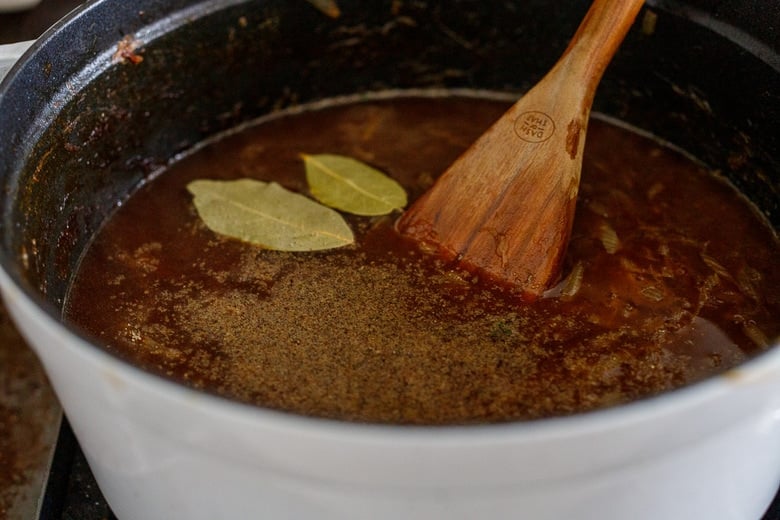 stir in the beef stock or veggie broth, bay leaves and pepper 