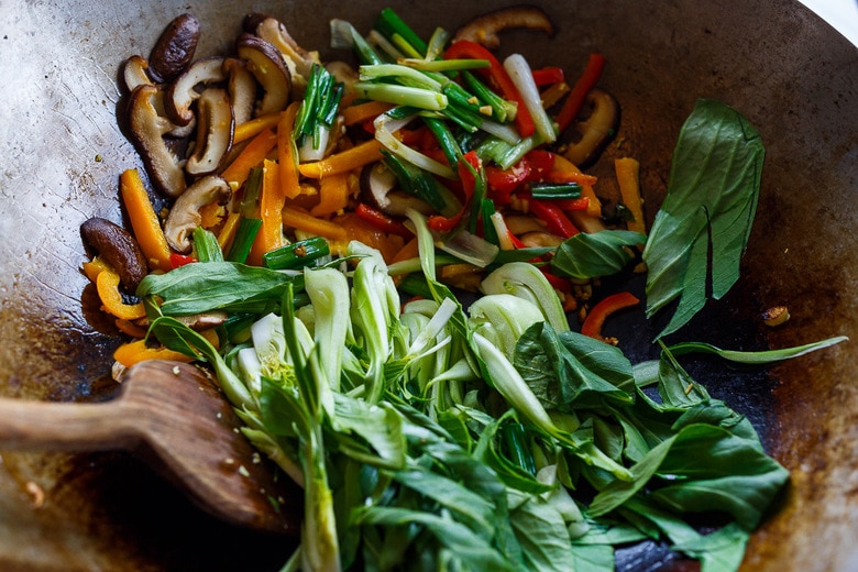 adding remaining ingredients to the wok