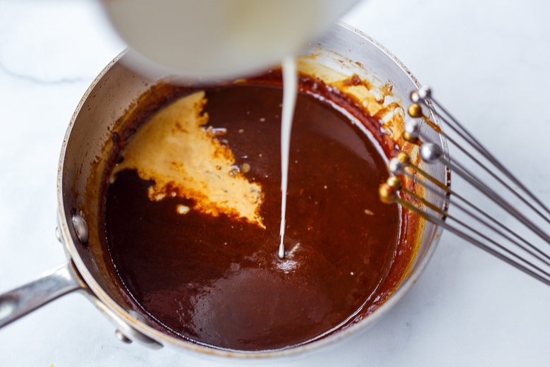 pouring cornstarch into sauce to heat