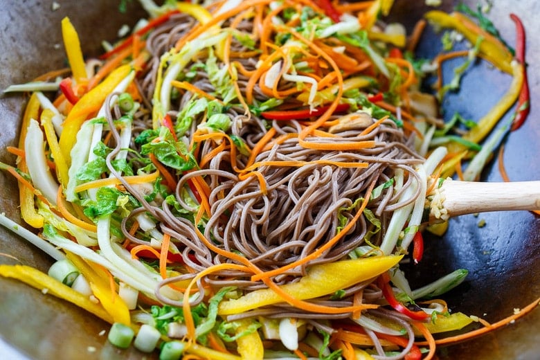 Adding soba noodles to the stirfry.