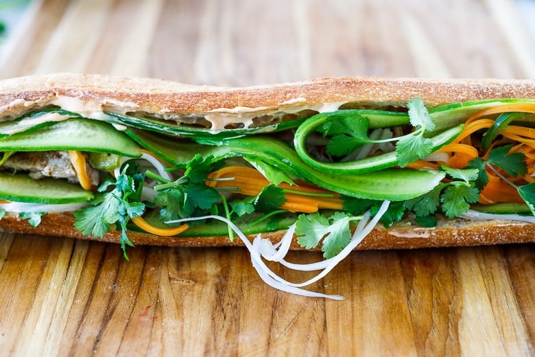 adding herbs, pickled veggies and fresh veggis to the banh mi