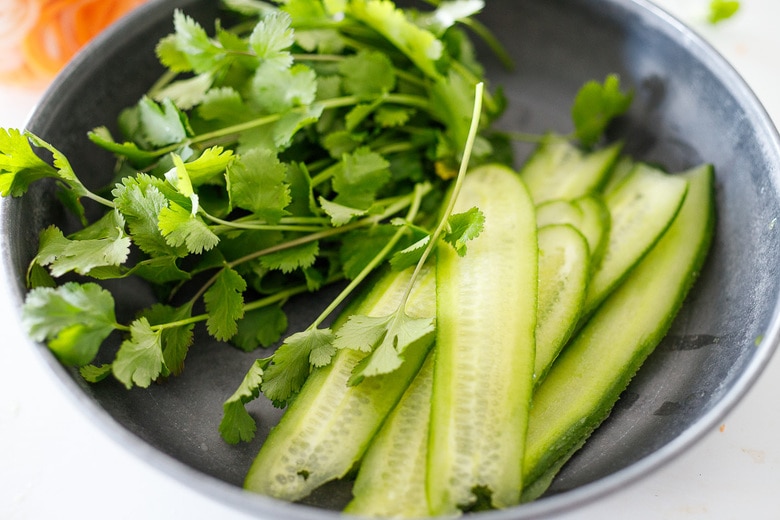 fresh herbs and cucumber in a bowl