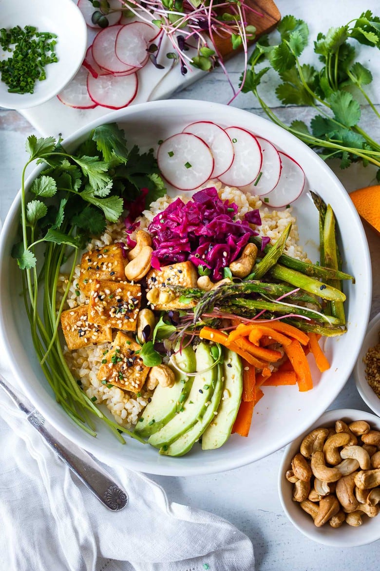 A delicious recipe for Miso Tofu and Veggies baked on a sheet pan in the oven, served over rice, with avocado, cashews radishes and flavorful miso dressing.