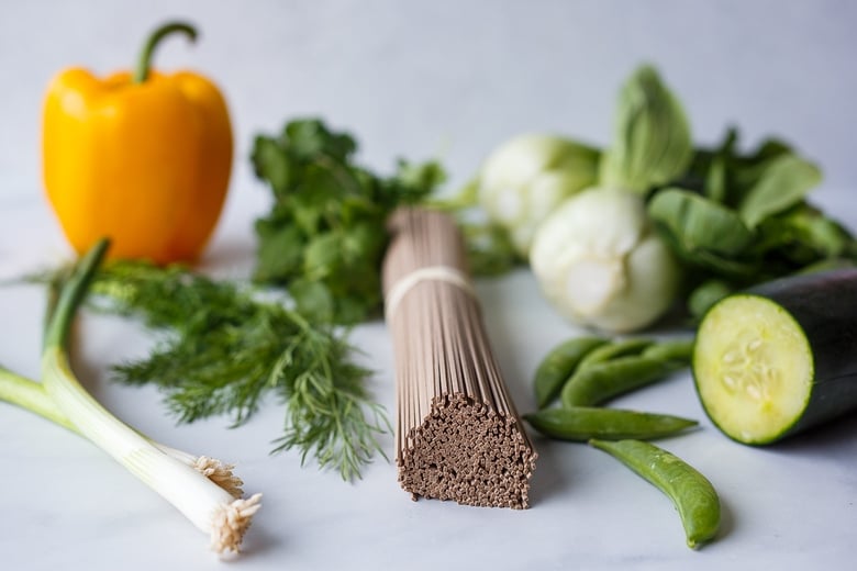 ingredients laid out for soba noodle salad- buckwheat soba noodles, cucumber, green onion, and veggies.