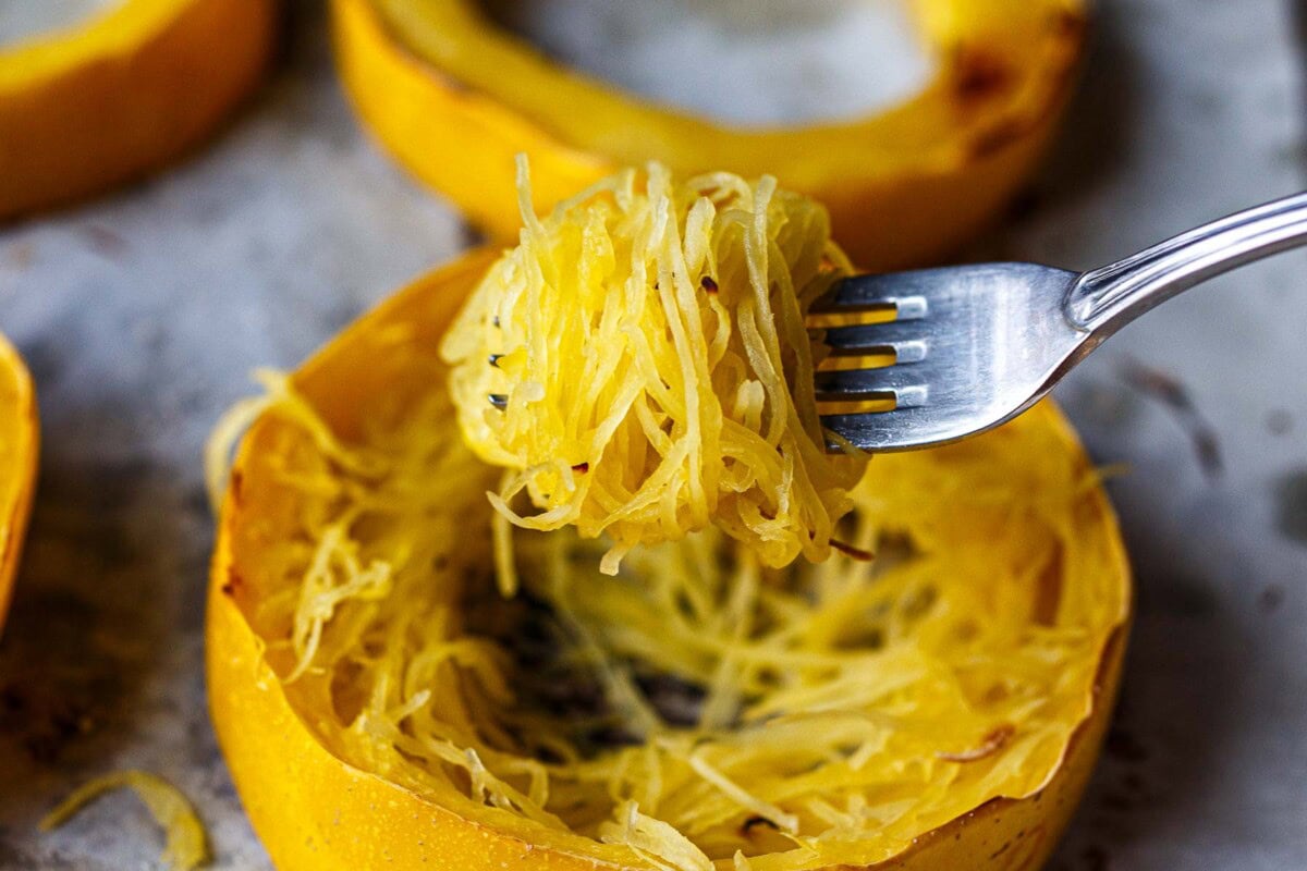 roasted squash rings on a parchment-lined baking sheet with fluffed spaghetti squash strands piled in the center of the rings.