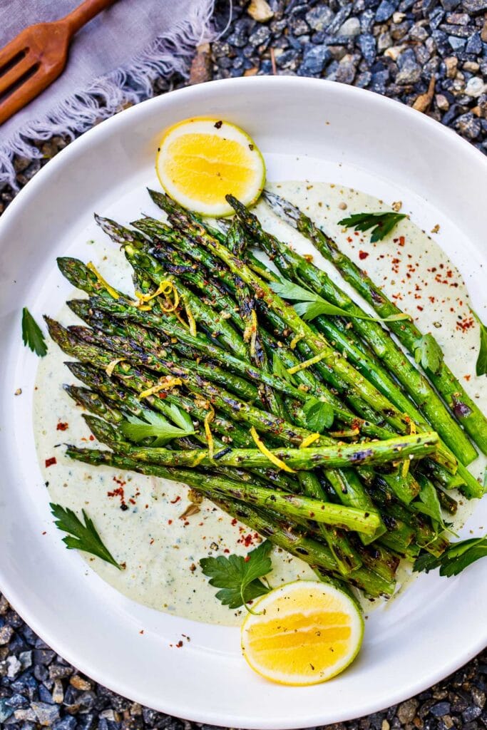 grilled asparagus with lemon zest over plate of dressing.