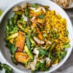 Delicious Coconut Rice Bowl is healthy and adaptable!  Curried jasmine rice cooked in coconut milk and topped with tofu or your choice of protein and seasonal vegetables.  All tossed with a simple, flavorful sauce, fresh cilantro, mint and toasted coconut flakes.