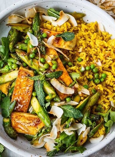 Delicious Coconut Rice Bowl is healthy and adaptable!  Curried jasmine rice cooked in coconut milk and topped with tofu or your choice of protein and seasonal vegetables.  All tossed with a simple, flavorful sauce, fresh cilantro, mint and toasted coconut flakes.