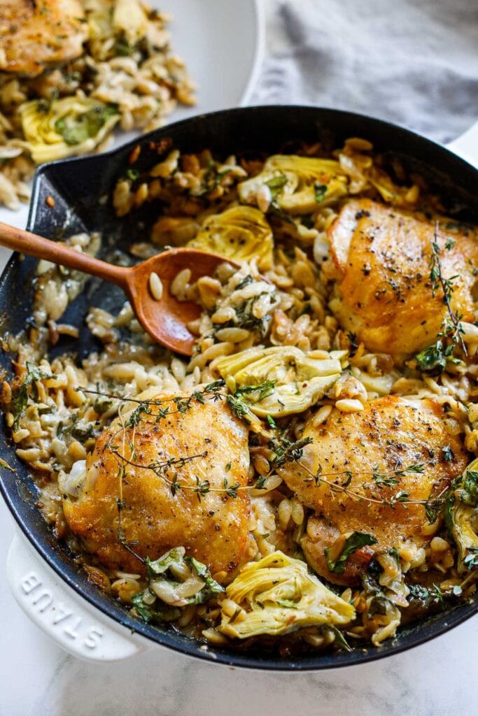 Our favorite Braised Chicken Thigh Recipes: One Skillet Creamy Orzo Chicken with Artichoke Hearts- a deliciously cozy dinner, made with simple pantry ingredients, perfect for busy weeknights.
